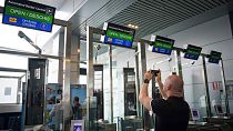 A man takes a picture of Non-Schengen automatic border control gates, at the Henri Coanda International Airport in Otopeni, near Bucharest, Romania, Thursday, March 28, 2024.