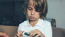 A child uses an insulin pen at the doctor's office.
