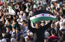 A Syrian man waves a revolutionary flag during a celebration in Damascus, 13 December, 2024