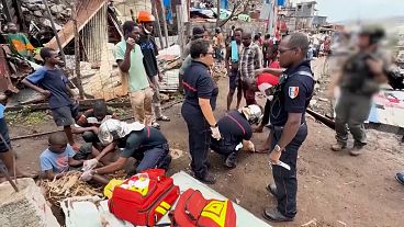 Medics tending to children as firefighters and security forces conduct search and rescue work