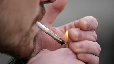A man smokes cannabis in Cologne, Germany, at a public consumption event at the start of a new law in April 2024. 