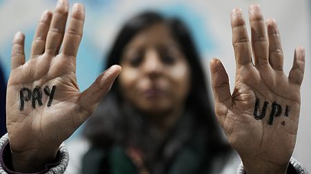 A demonstrator displays hands that read "pay up" during a protest for climate finance at the COP29 U.N. Climate Summit, Saturday, Nov. 23, 2024, in Baku, Azerbaijan.